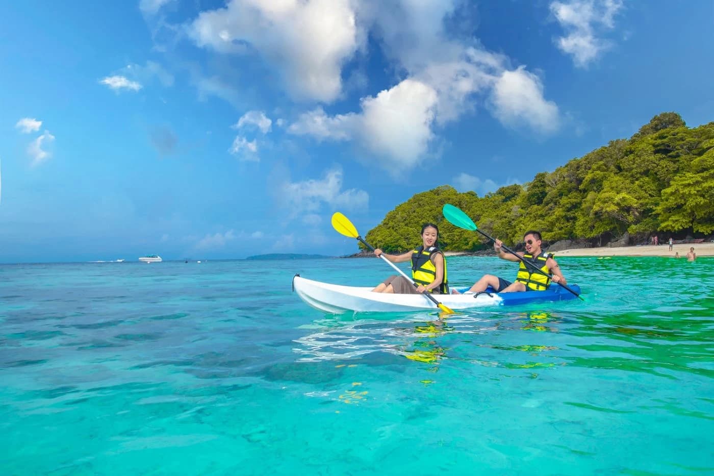 Two people kayaking on turquoise tropical waters near the island
