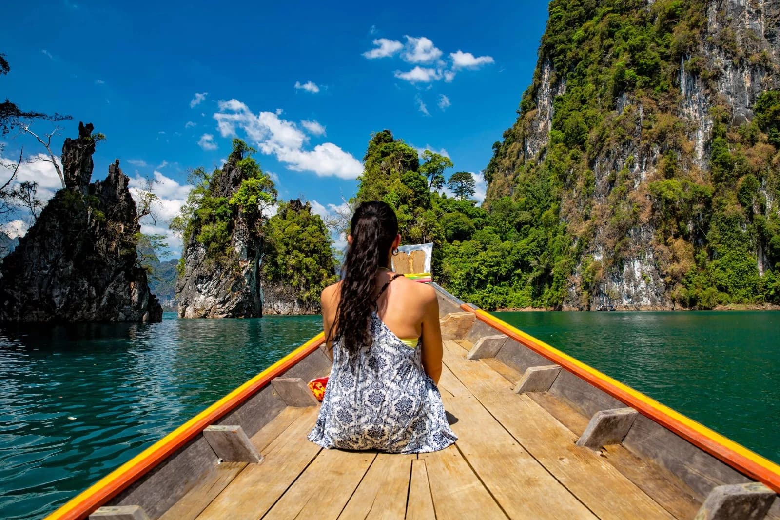 Woman on longtail boat bow facing limestone karsts in Cheow Lan Lake