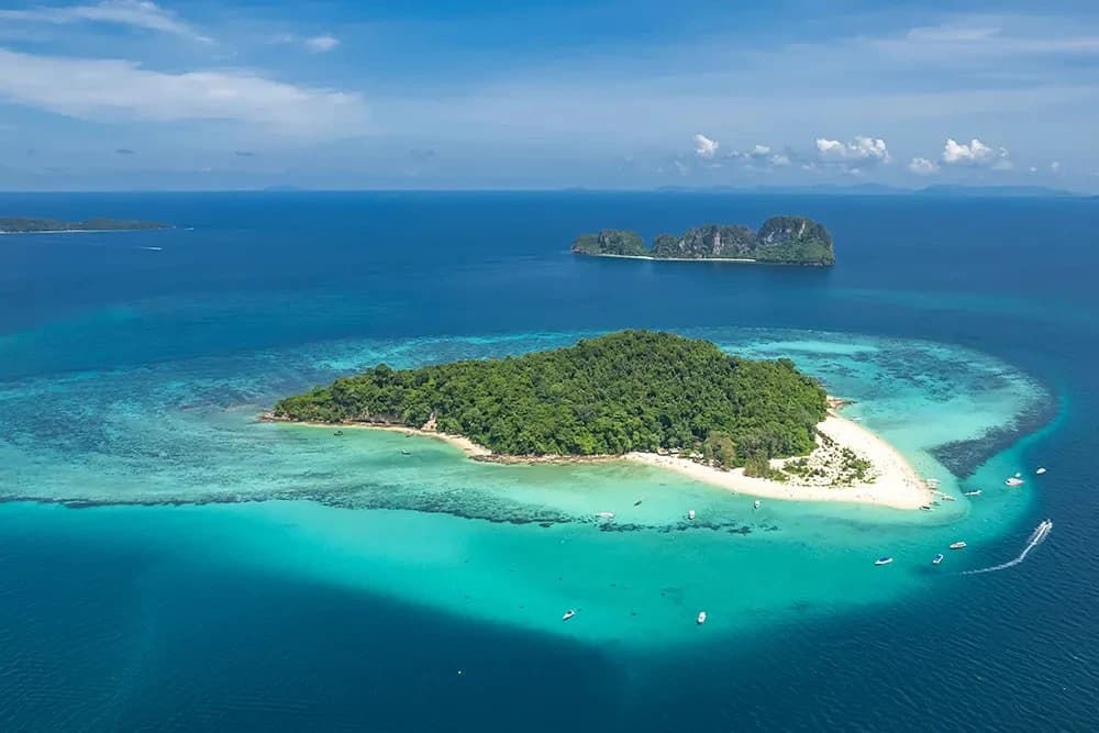 Aerial view of a tropical green island surrounded by turquoise waters
