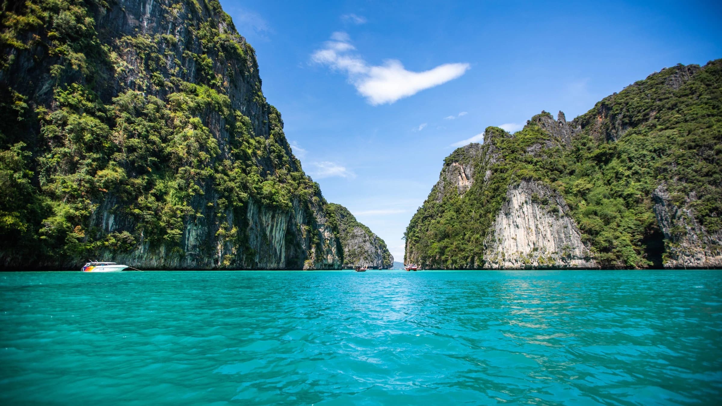 Turquoise sea framed by towering green limestone cliffs